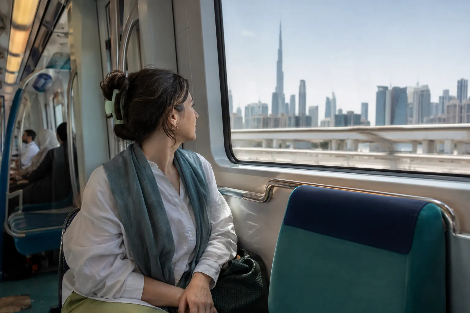 Traveler seated forward-facing by the window on a quiet Dubai Metro journey.