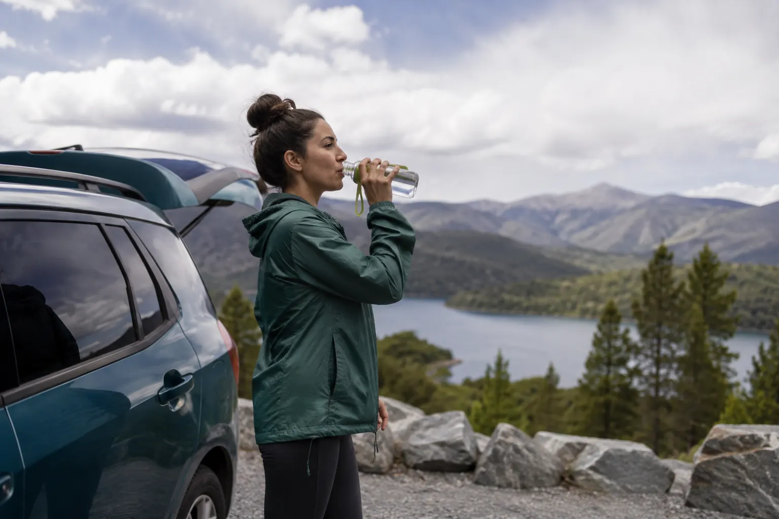Passenger taking a calm roadside break, looking into the distance and sipping water.