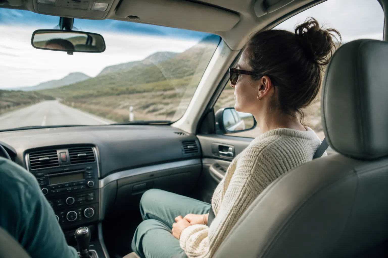 Front passenger looking toward a distant road with the phone put away and air vent open.