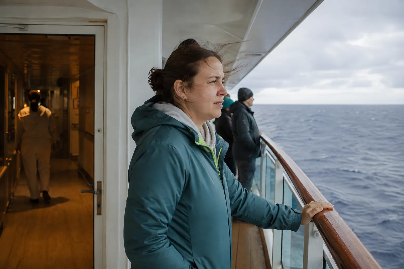 Cruise passenger moving to a sheltered midship deck and looking at the horizon during a crossing.