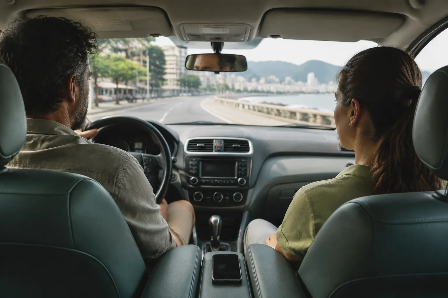 Rideshare passenger placing a phone face-down and looking forward through the windshield.