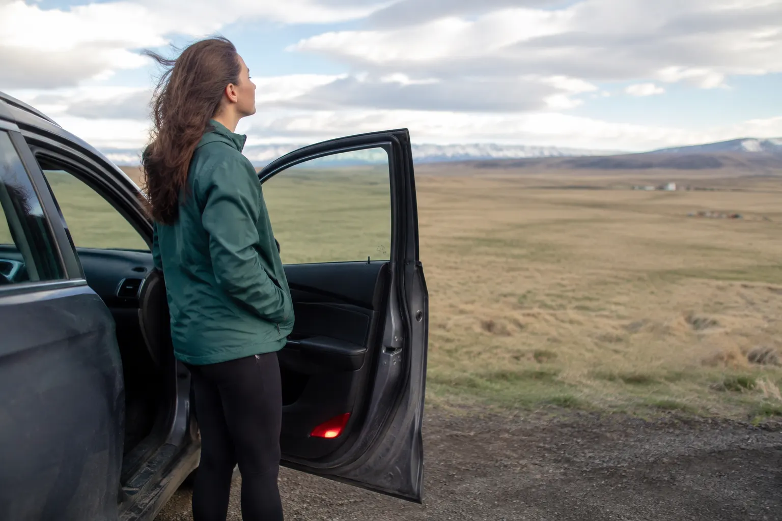 Car passenger getting fresh air beside an open door while the vehicle is safely parked.