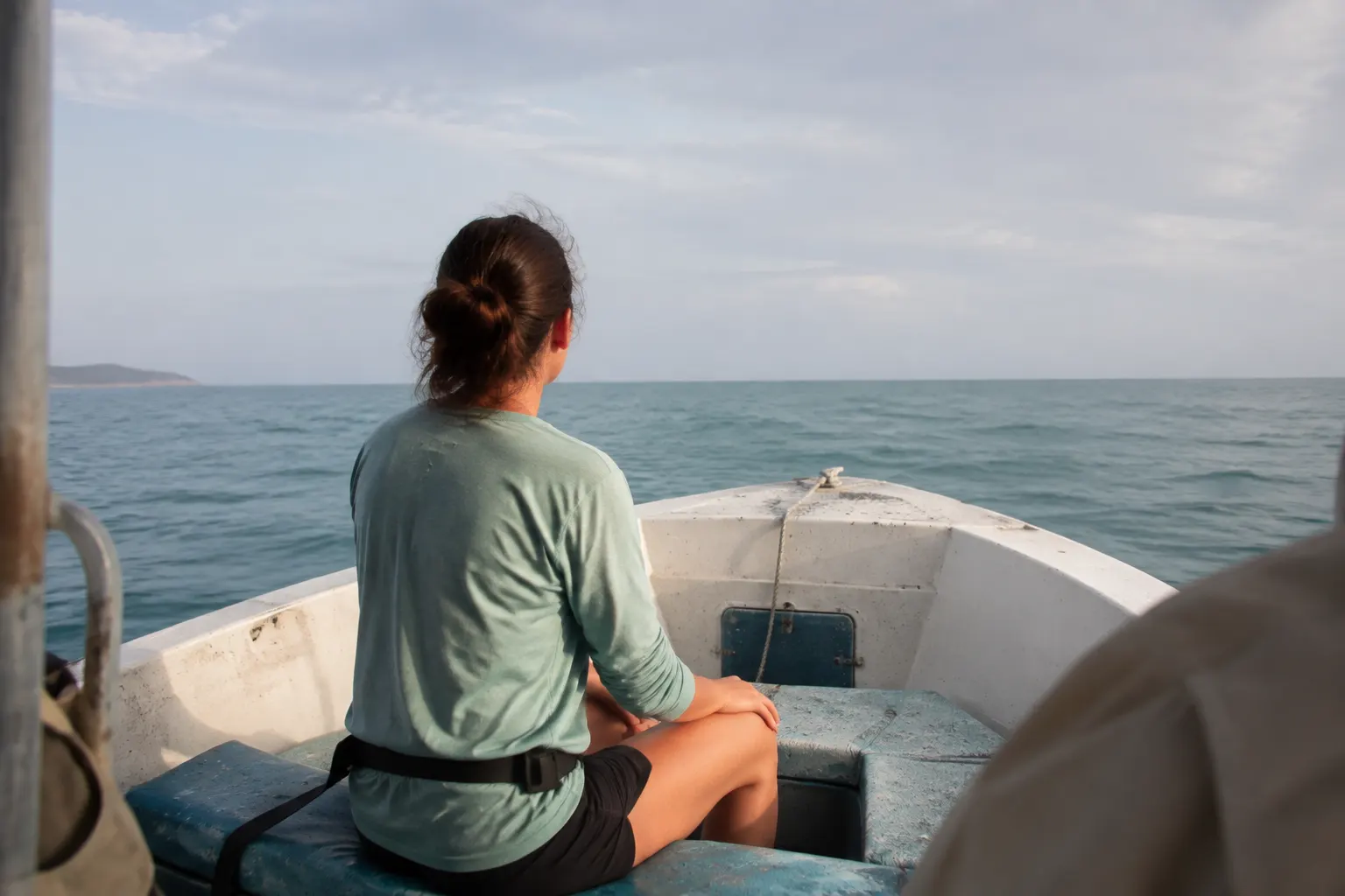 Small-boat passenger seated safely and looking at the distant horizon while underway.