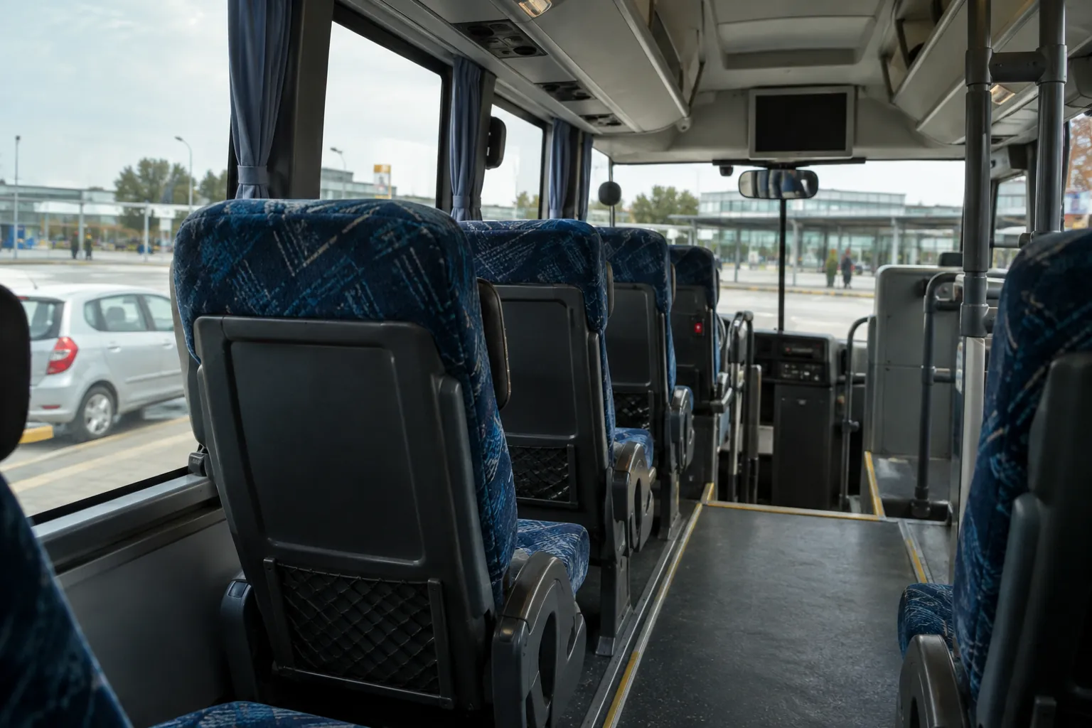 High bus seats and a limited forward view, with a lower parked car visible through the window.