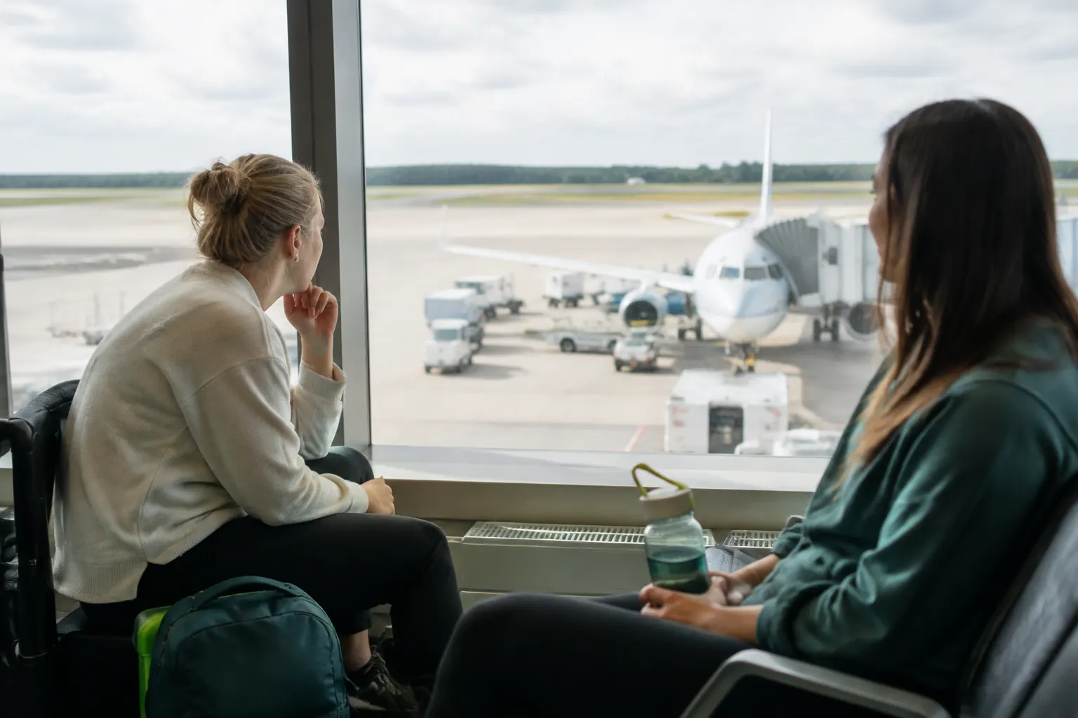 Nervous flyer watching an aircraft from the gate with a supportive companion nearby.