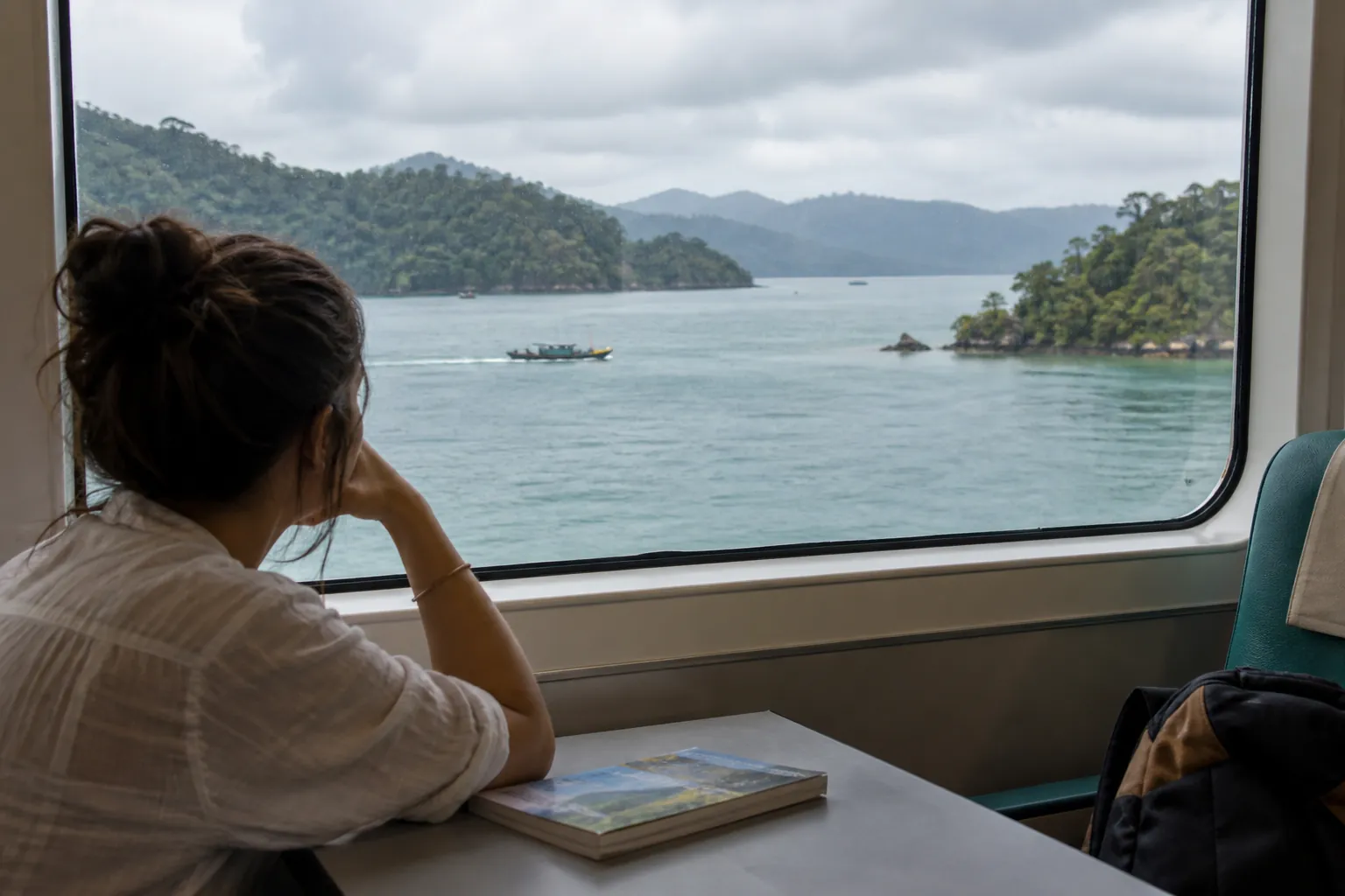 Low tropical shorelines surrounding a sheltered strait seen from a passenger lounge.