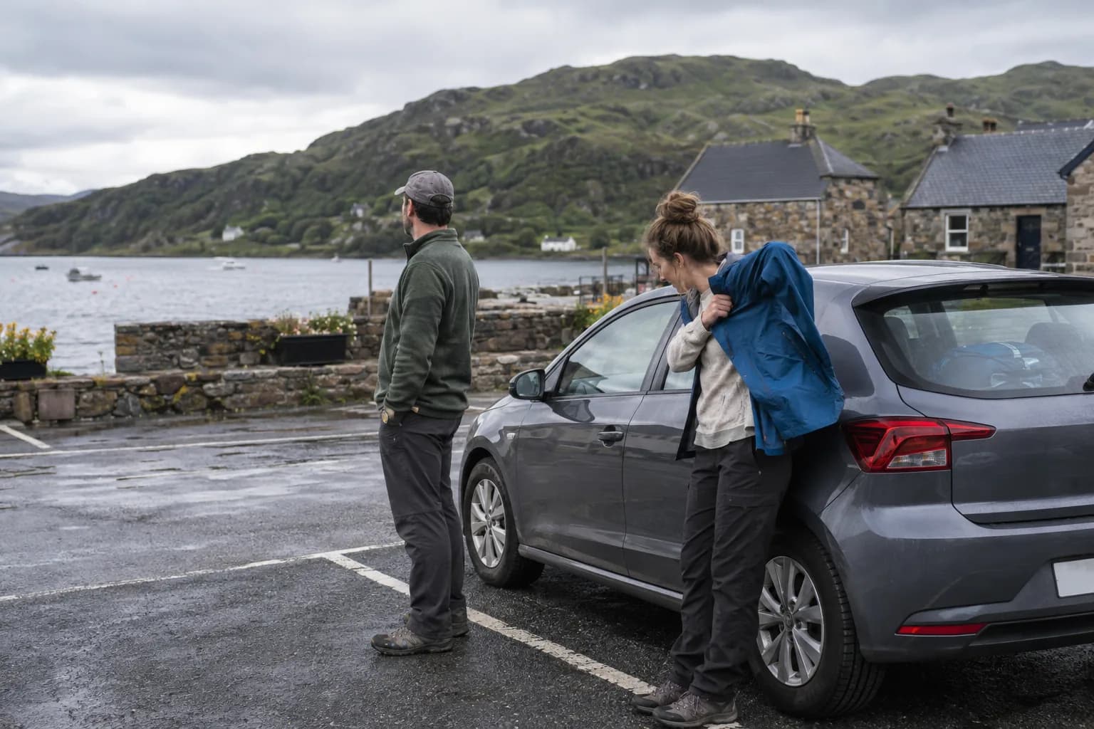 Travellers taking a village break beside a car parked in a proper parking area in the Highlands.